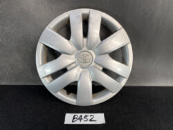 Silver Toyota hubcap with the emblem in the center, showing multiple surface Scratches on an eight-spoke design.