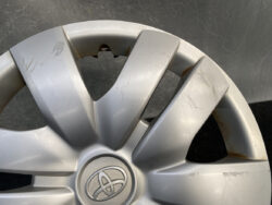 Silver Toyota hubcap with visible scratches and rust stains along the rim edge.