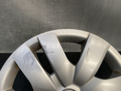 Close-up of a silver car alloy wheel with multiple scratches and scuffs on the rim surface.