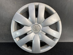 Silver Toyota hubcap with center logo and multiple scratch marks across the spokes.