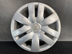 Silver Toyota wheel hubcap with visible scratches and scuffs, circular with logo at center