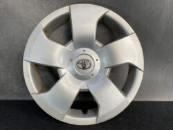 Silver Toyota hubcap with five-spoke design and central emblem; shows scratches and rust at the edges.