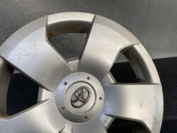 Close-up of a silver Toyota wheel hubcap with visible scratches and rust spots on the surface.