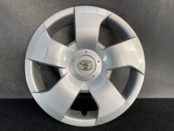 Silver Toyota wheel hubcap with five-spoke design, showing scratches and scuffs on the surface.