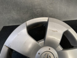 Silver Toyota wheel hubcap with surface scratches and scuffs on a dark background, close view.