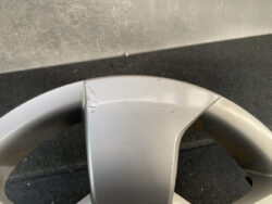 Close-up of a silver alloy car wheel rim with light scratches along the spoke junction.