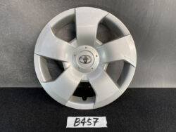 Silver Toyota hubcap with a five-spoke design and central Toyota emblem on a dark surface.