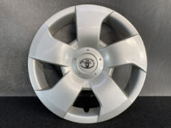 Silver Toyota wheel hubcap with five spokes on a dark surface