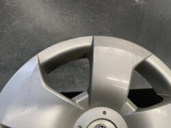 Close-up of a silver alloy wheel with noticeable scratches and scuffs around the spokes and hub area.