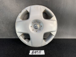 Silver Toyota hubcap on a black surface, center emblem visible, with minor scratches; label beneath reads B458.