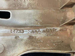 Close-up of a dusty metal casting with stamped identifiers, including 44733-SW4-N010-M, PP-GF20, and an AN mark.
