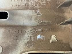 Close-up of a dusty beige plastic car part with stamped number 44733-SAA- NO40 MT and small embossed logos.