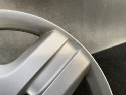 Close-up of a silver car alloy wheel rim with a small scratch and scuff along the outer edge.