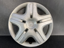 Silver Honda wheel hubcap with a five-spoke design, scratched and scuffed, center Honda emblem visible at the middle