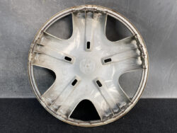 Honda wheel cover with five spokes, dusty and edge rust visible.