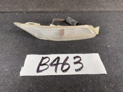 Clear/amber car side marker light lens with wiring harness, likely a bumper reflector component on a dark carpeted surface.