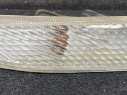 Close-up of a clear car tail light lens with a diagonal facet pattern and 'JAPAN R' engraving.