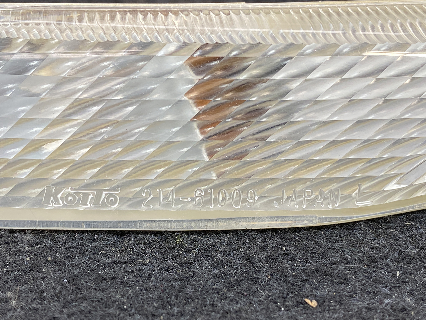 B464_2 MAZDA RX-8 SE3P Genuine Side Indicator KOITO 214-61009 Left Side x1 » NZ.95 » JDM-PARTS NZ » JDM-PARTS NZ Close-up of a diamond-patterned metal surface with an engraved inscription reading 'KOTTO 24-61009 JAPAN'. MAZDA RX-8 SE3P Genuine Side Indicator KOITO 214-61009 Left Side x1 » JDM-PARTS NZ