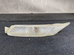 Clear plastic car side marker/indicator lens with a diamond pattern texture on a dark surface.