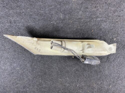 Beige automotive light housing with a wiring harness and plug, lying on a dark carpeted surface.
