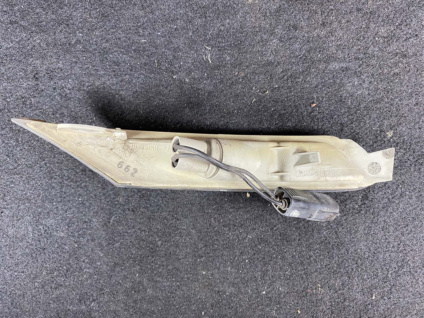 B464_4 MAZDA RX-8 SE3P Genuine Side Indicator KOITO 214-61009 Left Side x1 » NZ.95 » JDM-PARTS NZ » JDM-PARTS NZ Beige automotive light housing with a wiring harness and plug, lying on a dark carpeted surface. MAZDA RX-8 SE3P Genuine Side Indicator KOITO 214-61009 Left Side x1 » JDM-PARTS NZ