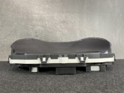 Detached curved car instrument cluster with a large black display panel on a base, likely a dashboard gauge unit