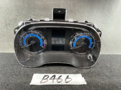 Vehicle dashboard instrument cluster: left tachometer, right speedometer, and central display with a glossy black bezel.