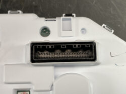 Close-up of a white plastic electronic module showing a large rectangular multi-pin connector port with many pins, no cover present.