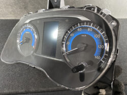 Car instrument cluster with speedometer up to 140 km/h and blue accents, plus a central display panel behind a clear cover.