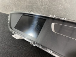 Clear protective frame around a blank car infotainment screen resting on a dark surface, with mounting tabs visible