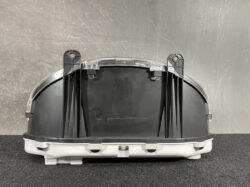Rear view of a curved black automotive housing with mounting posts and clear clips, resting on a white base on a gray surface.