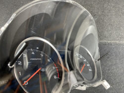 Close-up of a car instrument cluster showing the tachometer and speedometer behind a clear bezel.