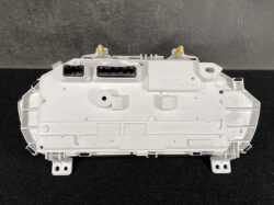White plastic automotive control module with two rectangular connectors and yellow locking clips on top, viewed from the back (likely a car dashboard unit).