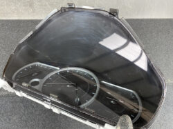 Car instrument cluster inside a curved plastic housing, showing speedometer and tachometer.