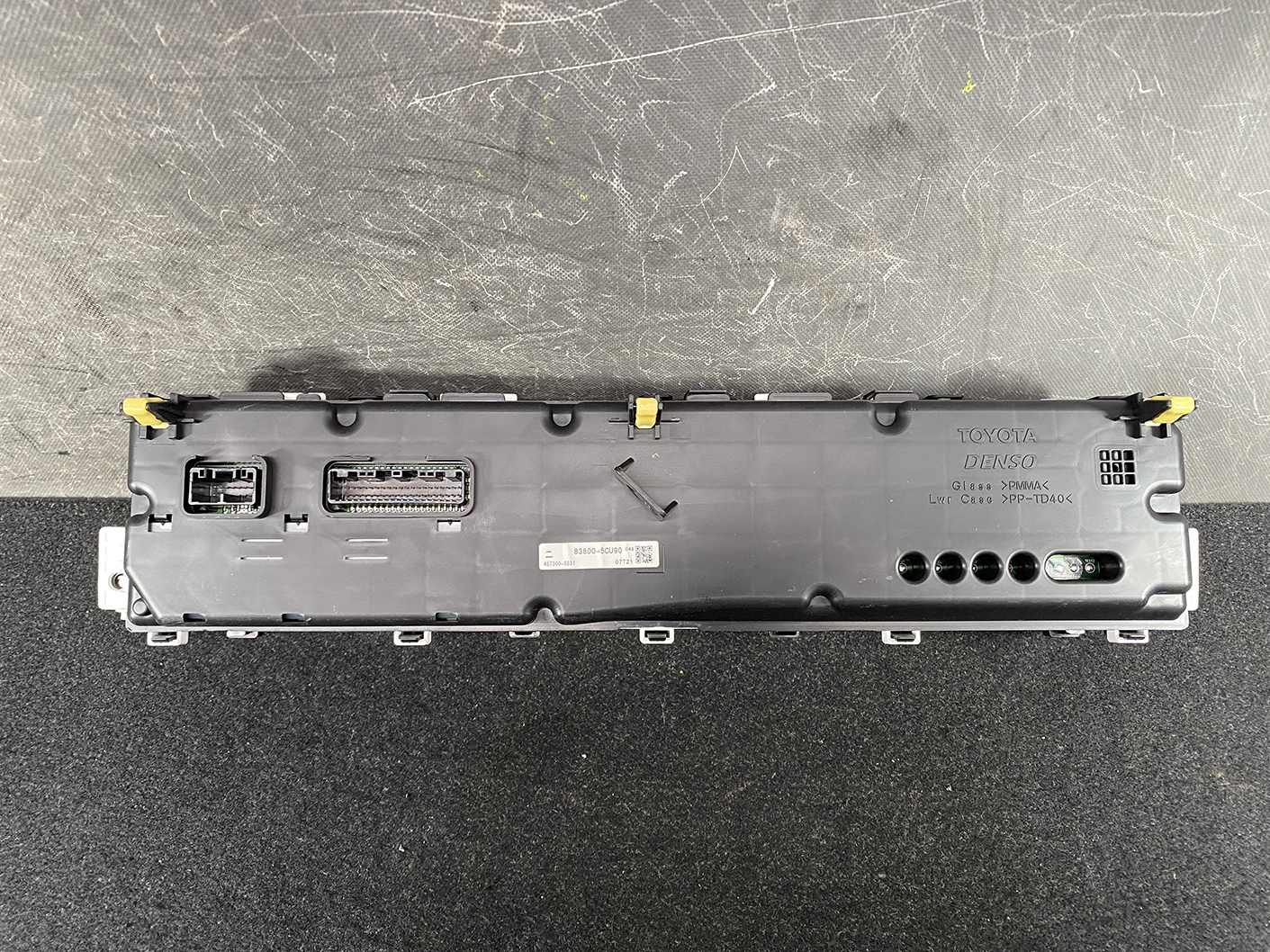 B473_6 TOYOTA PRIUS C AQUA NHP10 Genuine Instrument Cluster 83800-5CU90 » NZ1.95 » JDM-PARTS NZ » JDM-PARTS NZ Rear view of a Toyota instrument cluster module with multiple connectors and mounting tabs. TOYOTA PRIUS C AQUA NHP10 Genuine Instrument Cluster 83800-5CU90 » JDM-PARTS NZ