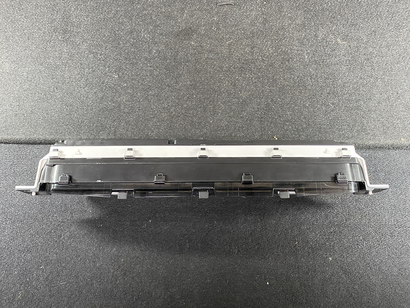 B473_8 TOYOTA PRIUS C AQUA NHP10 Genuine Instrument Cluster 83800-5CU90 » NZ1.95 » JDM-PARTS NZ » JDM-PARTS NZ Long black automotive electronic module with multiple plastic clips, resting on a dark textured surface (likely a vehicle control unit). TOYOTA PRIUS C AQUA NHP10 Genuine Instrument Cluster 83800-5CU90 » JDM-PARTS NZ