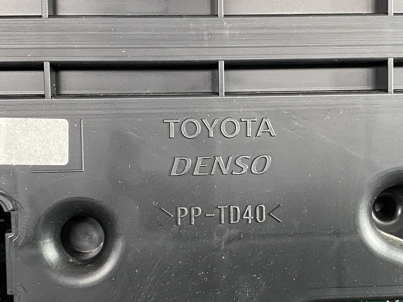 B474_4 TOYOTA SIENTA NHP170 Genuine Instrument Cluster 83800-5CP61 » NZ1.95 » JDM-PARTS NZ » JDM-PARTS NZ Close-up of a black plastic car engine cover showing the brand markings TOYOTA and DENSO with PP-TD40. TOYOTA SIENTA NHP170 Genuine Instrument Cluster 83800-5CP61 » JDM-PARTS NZ