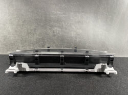 Automotive instrument cluster module with clear lens and plastic mounting brackets.