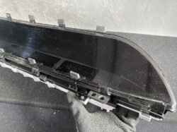Curved car instrument cluster screen with mounting clips during removal.
