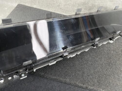 Detached car infotainment display panel with edge mounting clips on a workshop surface