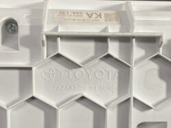 White plastic panel featuring embossed TOYOTA YAZAKI METER branding with a hexagonal lattice pattern and a visible screw inset.