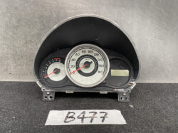 Car instrument cluster with central speedometer and left tachometer, digital display to the right, mounted on a black dashboard panel.