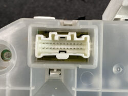 Close-up of a white multi-pin electrical connector inside a gray plastic housing, showing two rows of small pins.
