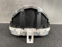 Back view of a circular automotive instrument cluster housing with gray plastic base and black interior supports, showing mounting tabs and a clear cover edge.
