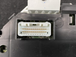 Close-up of a white rectangular multi-pin connector in a black housing, showing two rows of gold contact pins on a circuit board.