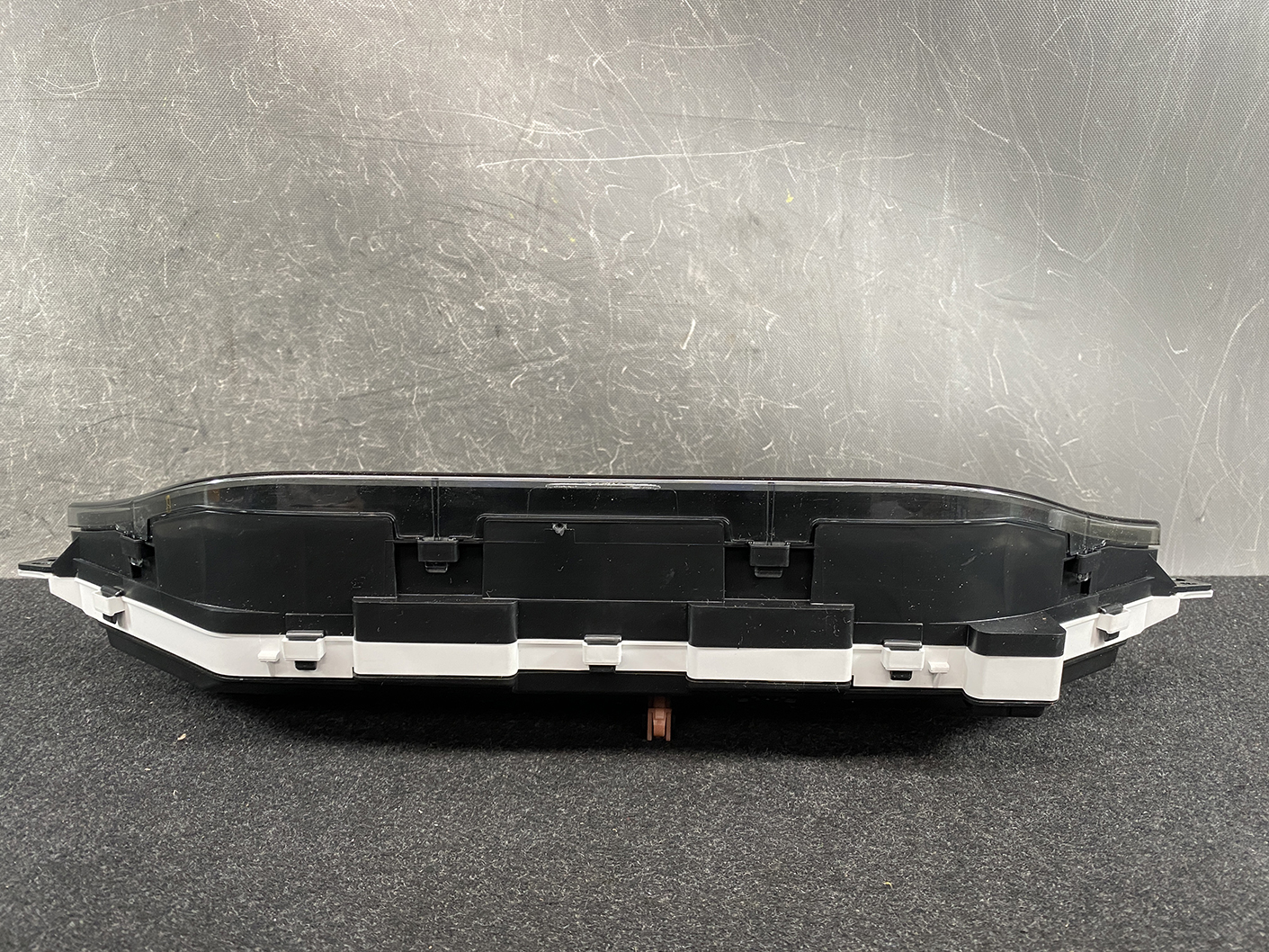 B479_7 SUZUKI SOLIO MITSUBISHI DELICA D2 Instrument Cluster 34111-81PS0 / 34104-81PA » NZ1.95 » JDM-PARTS NZ » JDM-PARTS NZ Detached car instrument cluster housing with a clear lens resting on a dark surface, black and white plastic trim visible. SUZUKI SOLIO MITSUBISHI DELICA D2 Instrument Cluster 34111-81PS0 / 34104-81PA » JDM-PARTS NZ