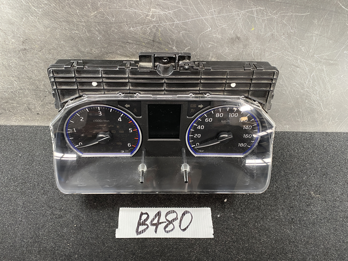 B480_2 NISSAN NV350 CARAVAN E26 Genuine Instrument Cluster 3YB0D TYPE: 883B » NZ1.95 » JDM-PARTS NZ » JDM-PARTS NZ Vehicle instrument cluster with two round gauges (tachometer and speedometer) and a central display, housed in a black plastic dash unit with a clear plastic cover. NISSAN NV350 CARAVAN E26 Genuine Instrument Cluster 3YB0D TYPE: 883B » JDM-PARTS NZ