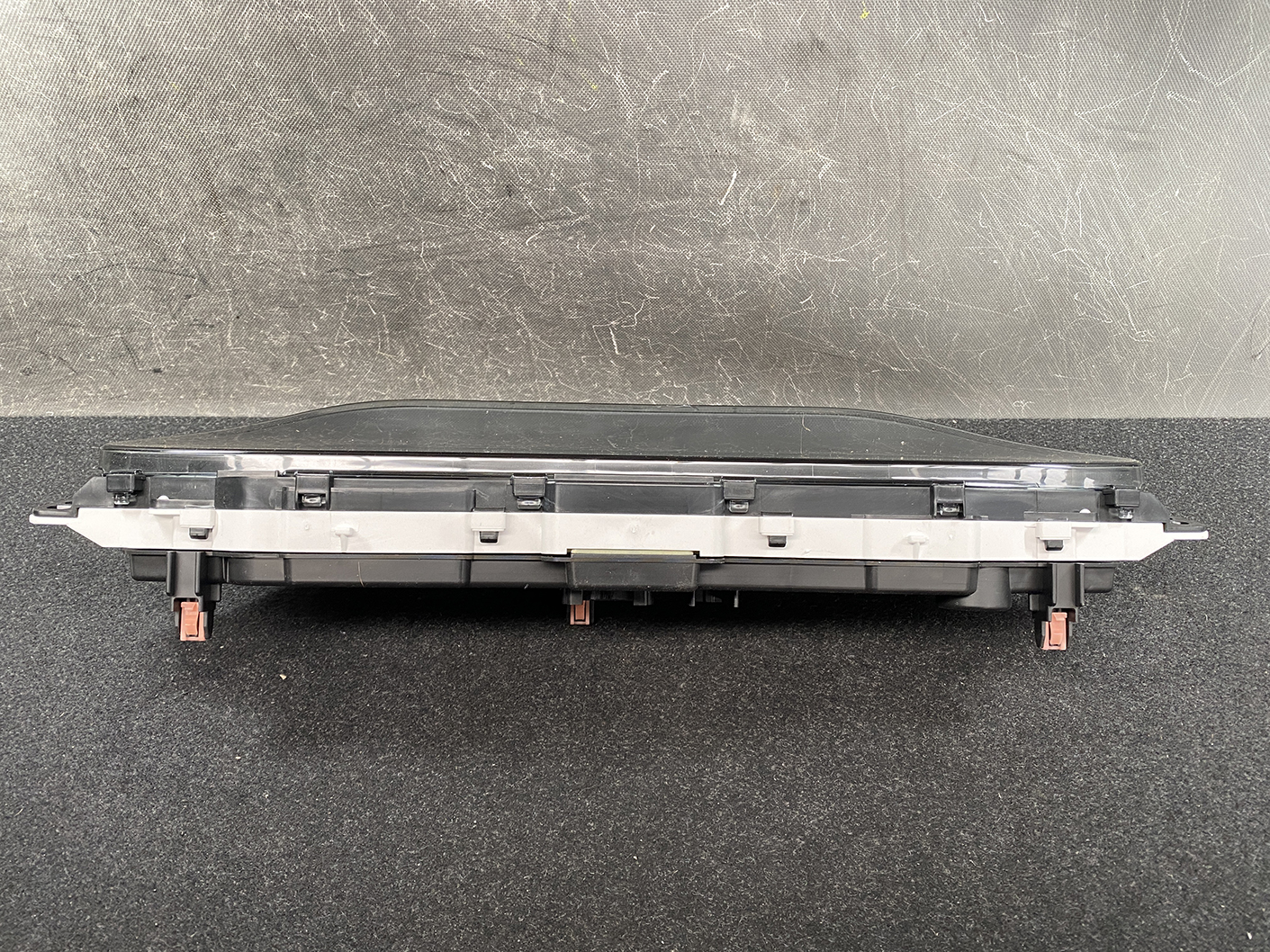 B481_6 SUZUKI SOLIO MITSUBISHI DELICA D2 Instrument Cluster 34110-81PN0 / 34102-81PA » NZ1.95 » JDM-PARTS NZ » JDM-PARTS NZ Long black automotive electrical module with orange-red connector latches at both ends and a metal mounting strip along the middle, shown from the side on a dark surface. SUZUKI SOLIO MITSUBISHI DELICA D2 Instrument Cluster 34110-81PN0 / 34102-81PA » JDM-PARTS NZ