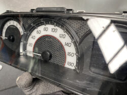Close-up of a car instrument cluster showing a speedometer up to 180 km/h; needle at rest near 0, with a secondary tachometer visible on the left.
