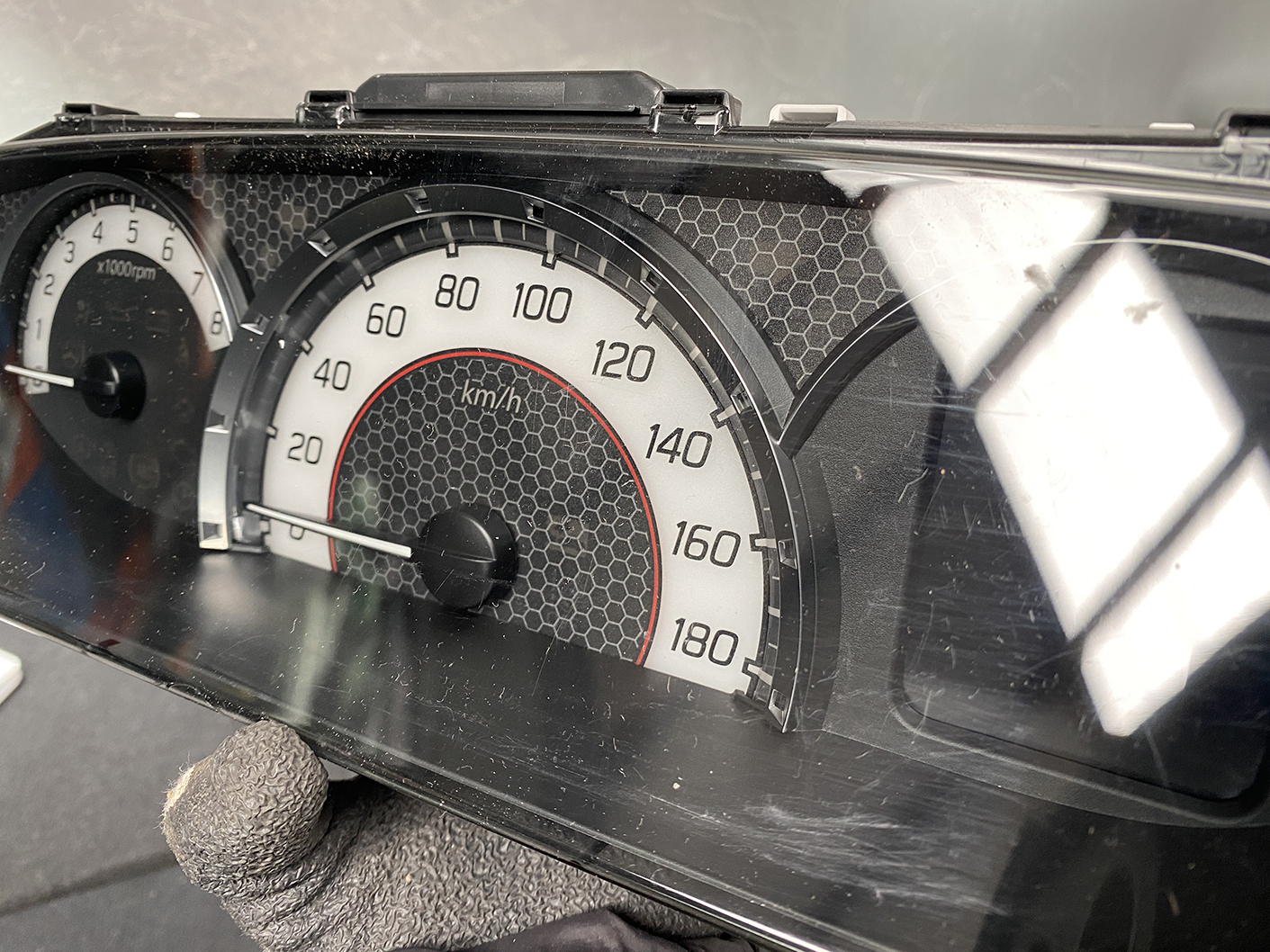 B481_9 SUZUKI SOLIO MITSUBISHI DELICA D2 Instrument Cluster 34110-81PN0 / 34102-81PA » NZ1.95 » JDM-PARTS NZ » JDM-PARTS NZ Close-up of a car instrument cluster showing a speedometer up to 180 km/h; needle at rest near 0, with a secondary tachometer visible on the left. SUZUKI SOLIO MITSUBISHI DELICA D2 Instrument Cluster 34110-81PN0 / 34102-81PA » JDM-PARTS NZ